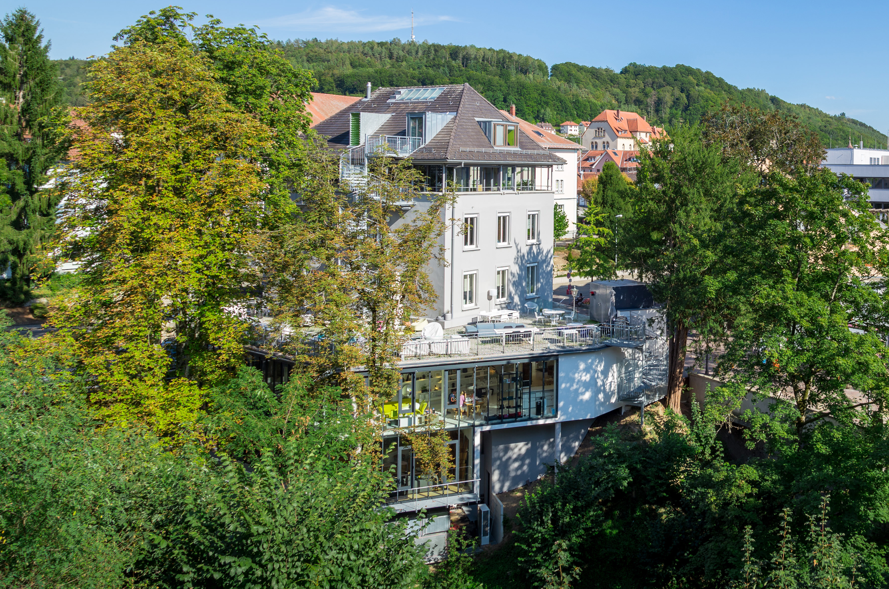 Blick auf Einrichtungshaus Seipp Wohnen Waldshut Blick auf das Einrichtungshaus Seipp Wohnen in Waldshut, umgeben von Bäumen, mit sichtbarer Terrasse und moderner Fassade.