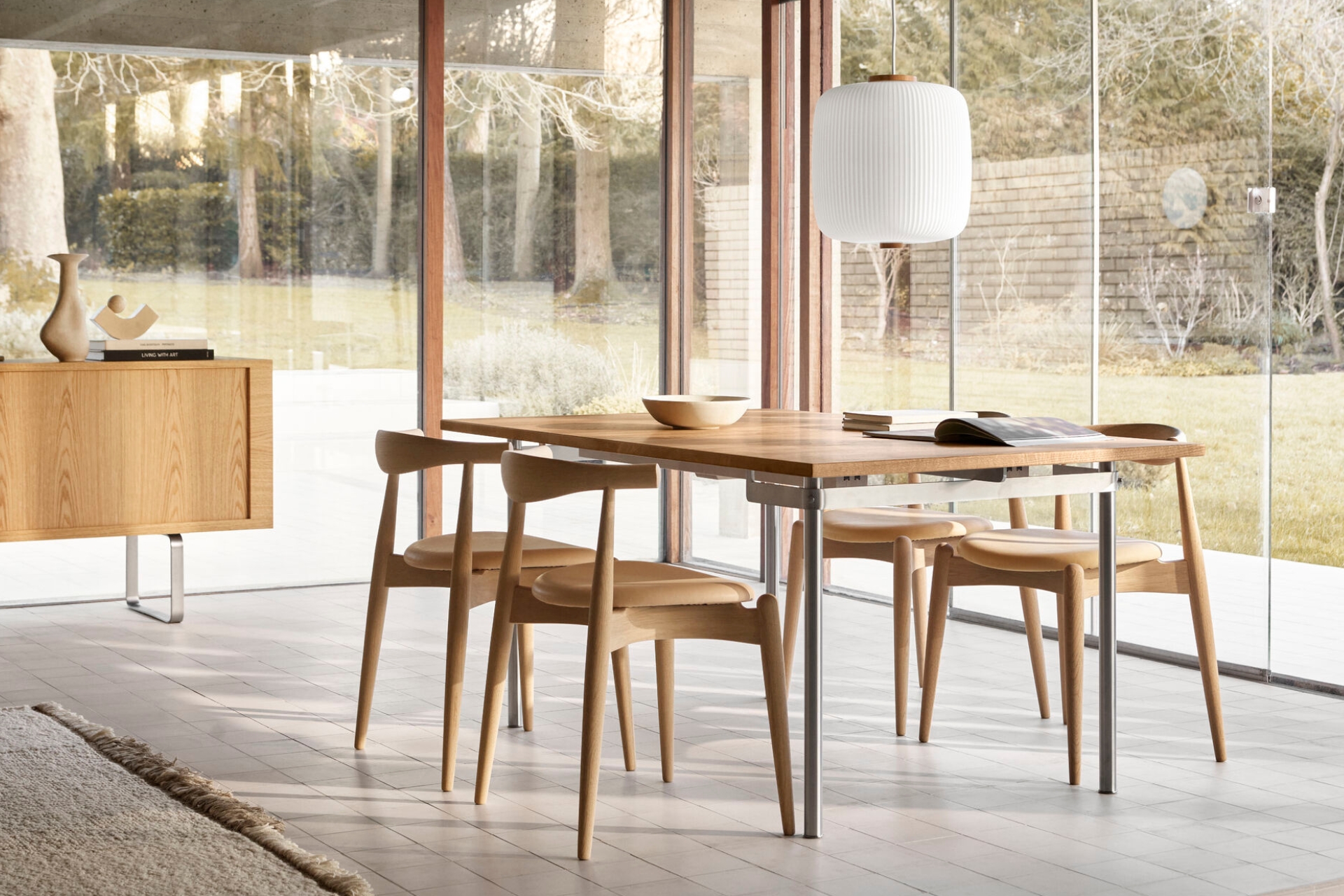 Essgruppe von Carl Hansen & Søn mit Holzstühlen und -tisch in modernem Raum mit Glasfront und Gartenblick.