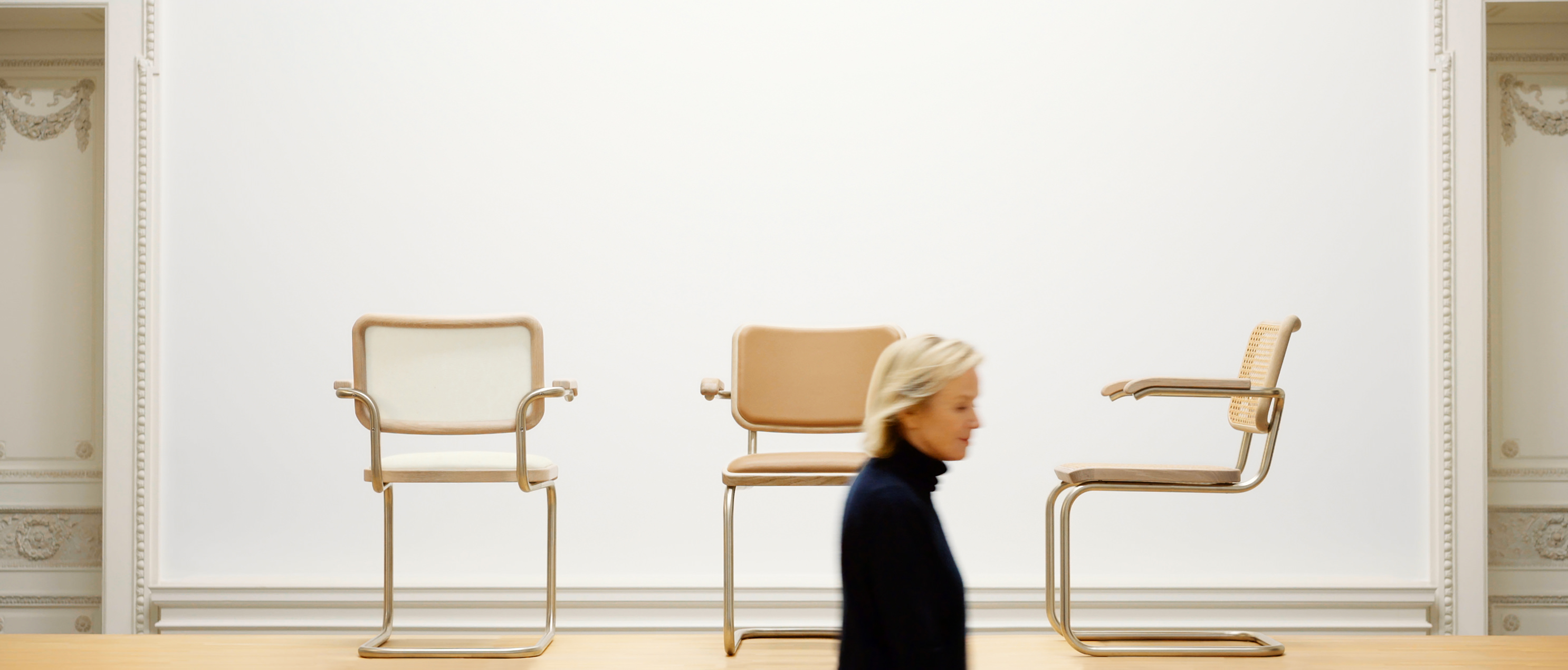 Das Bild zeigt die J. & S. THONET Edition des Stuhls S 64, neu interpretiert von der Designerin Jil Sander. Die minimalistischen, eleganten Freischwinger stehen prominent in einem hellen Raum, während Jil Sander selbst im Vordergrund zu sehen ist.