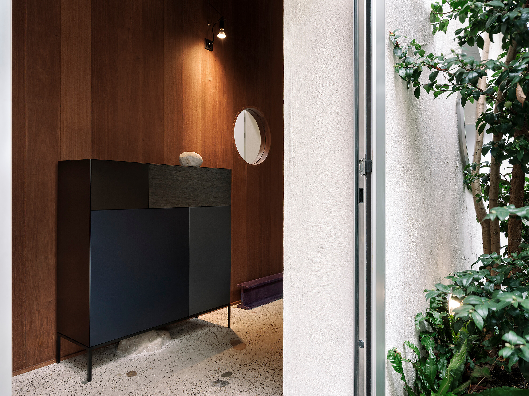 Dunkle Kommode mit klaren Linien in einer Nische mit Holzwandverkleidung