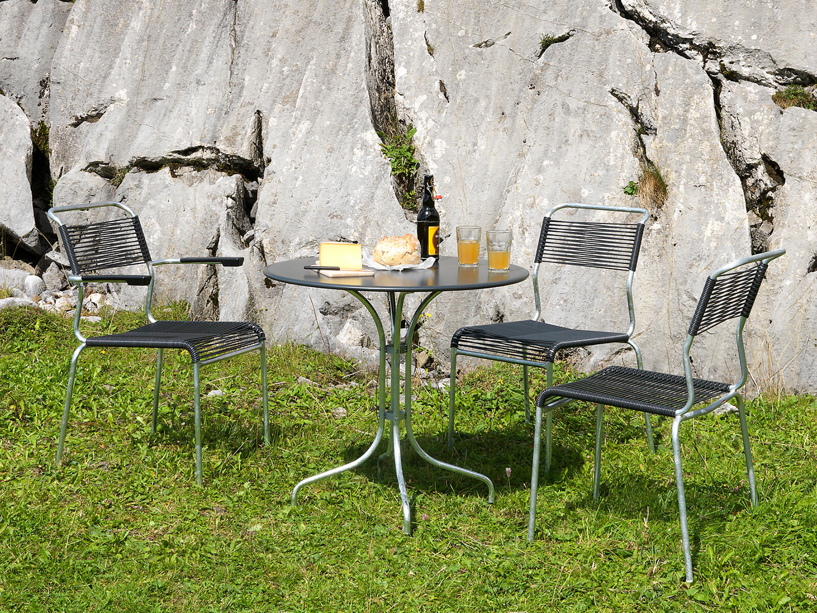 Gartenmöbel-Set aus Metall und Kunststoff mit runder Tischplatte auf Rasenfläche