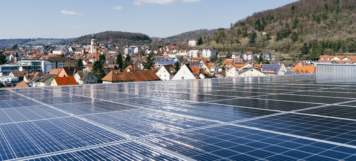 Nachhaltige Energie für Tiengen – Photovoltaik bei Seipp Wohnen Photovoltaikanlage auf dem Dach von Seipp Wohnen in Tiengen, im Hintergrund Stadtansicht und bewaldete Hügel des südlichen Schwarzwalds.