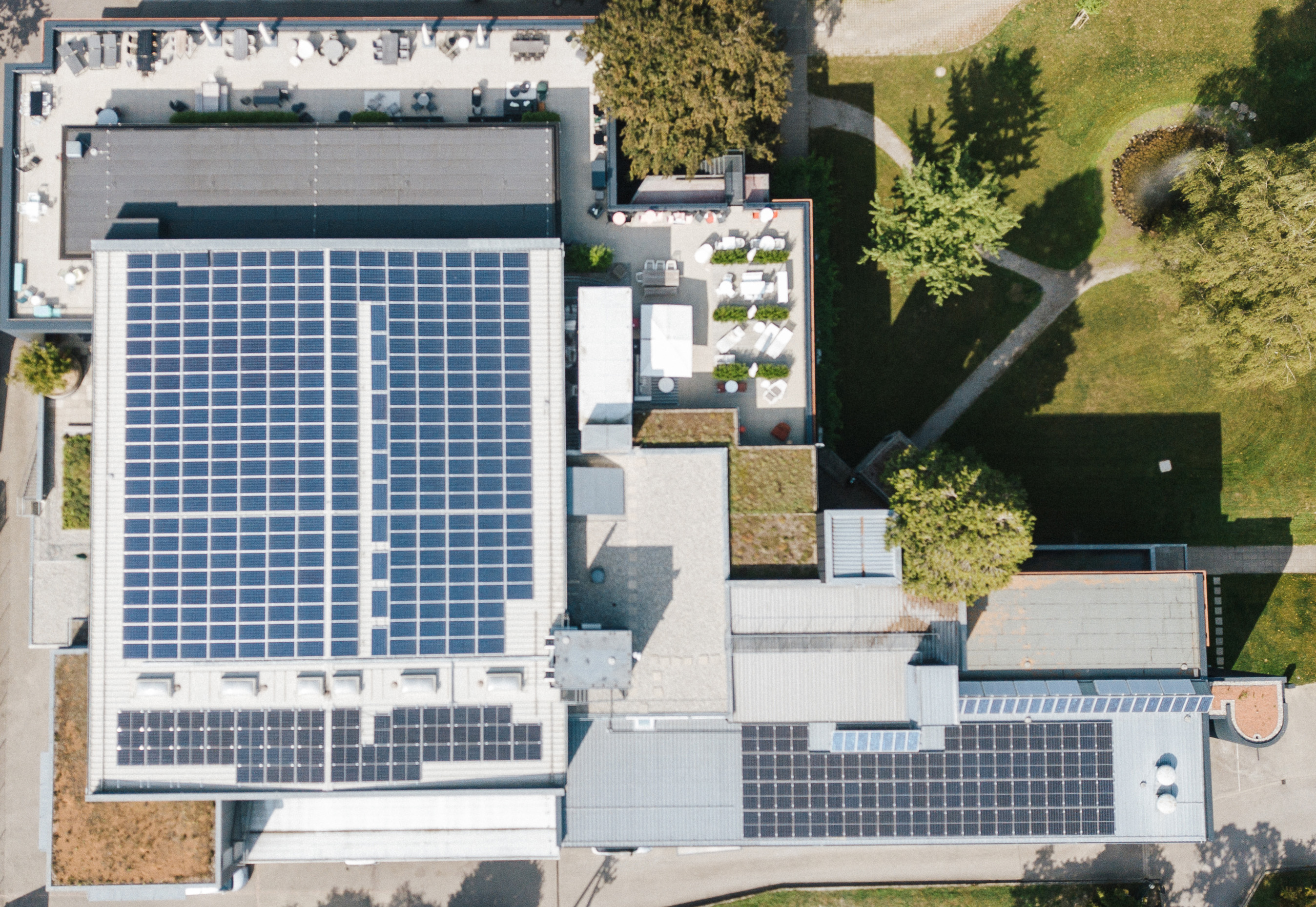 Luftaufnahme des Einrichtungshauses Seipp Wohnen in Tiengen mit großflächiger Photovoltaikanlage auf dem Dach. Draufsicht auf das Seipp Gebäude in Tiengen mit mehreren Dachflächen, die mit Photovoltaikmodulen zur Stromgewinnung bestückt sind.