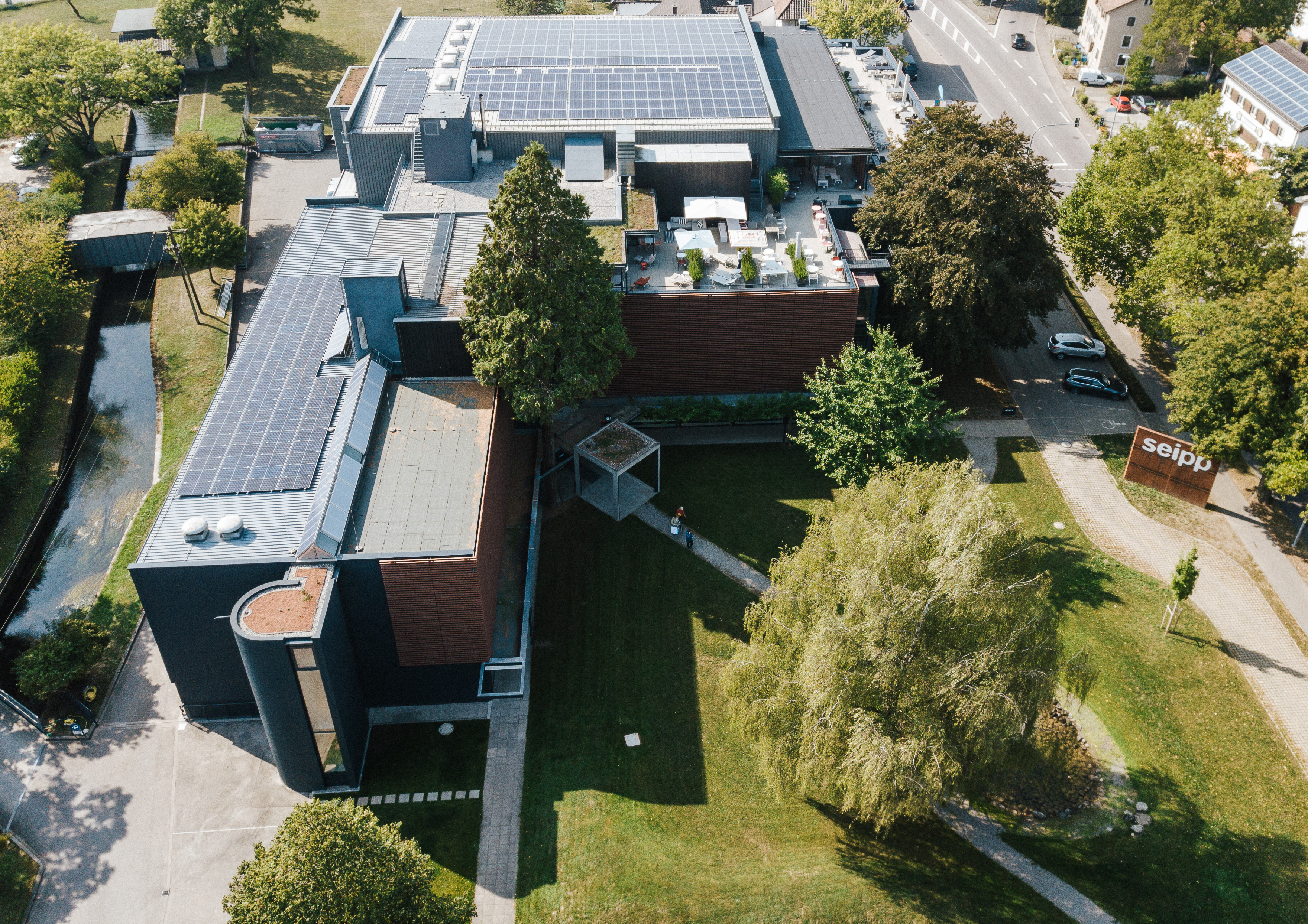 Das Einrichtungshaus Seipp Wohnen in Tiengen aus der Vogelperspektive – mit begrünten Außenflächen, Dachterrasse und Solarpanels. Luftaufnahme von Seipp Wohnen in Tiengen mit Photovoltaikanlage, Dachterrasse und begrünter Außenfläche am modernen Gebäudekomplex.